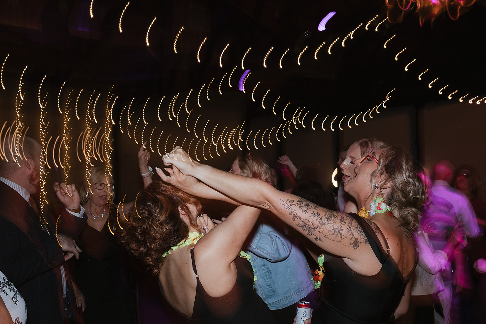 Guests dancing under lights at reception
