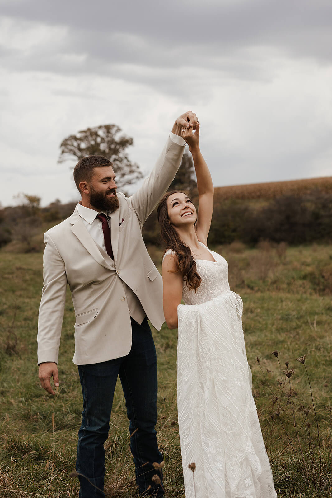 Bride and groom laughing and dancing together in an open field during Lancaster Wisconsin farmhouse wedding portraits