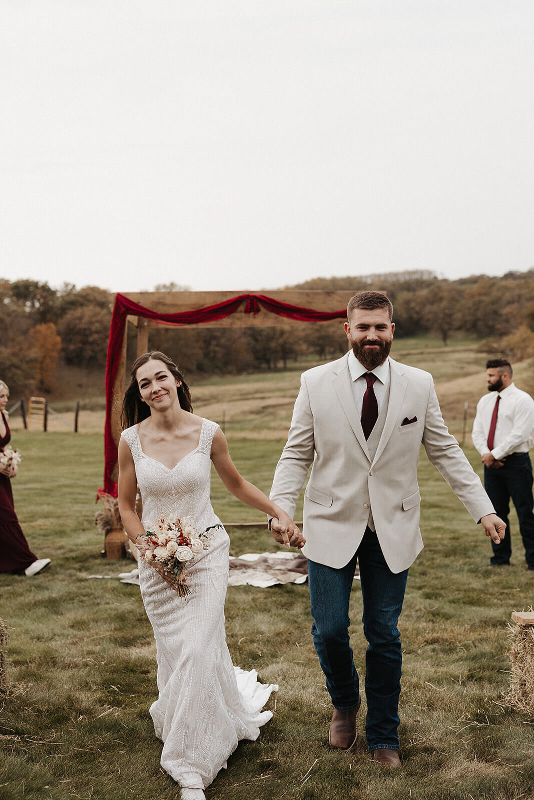 Bride and groom walking hand in hand after their outdoor ceremony at a Lancaster Wisconsin farmhouse wedding