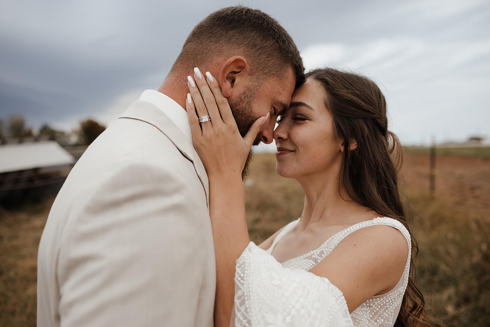 Bride and groom sharing a quiet moment with foreheads nearly touching during Lancaster Wisconsin farm wedding portraits with a barn in the background