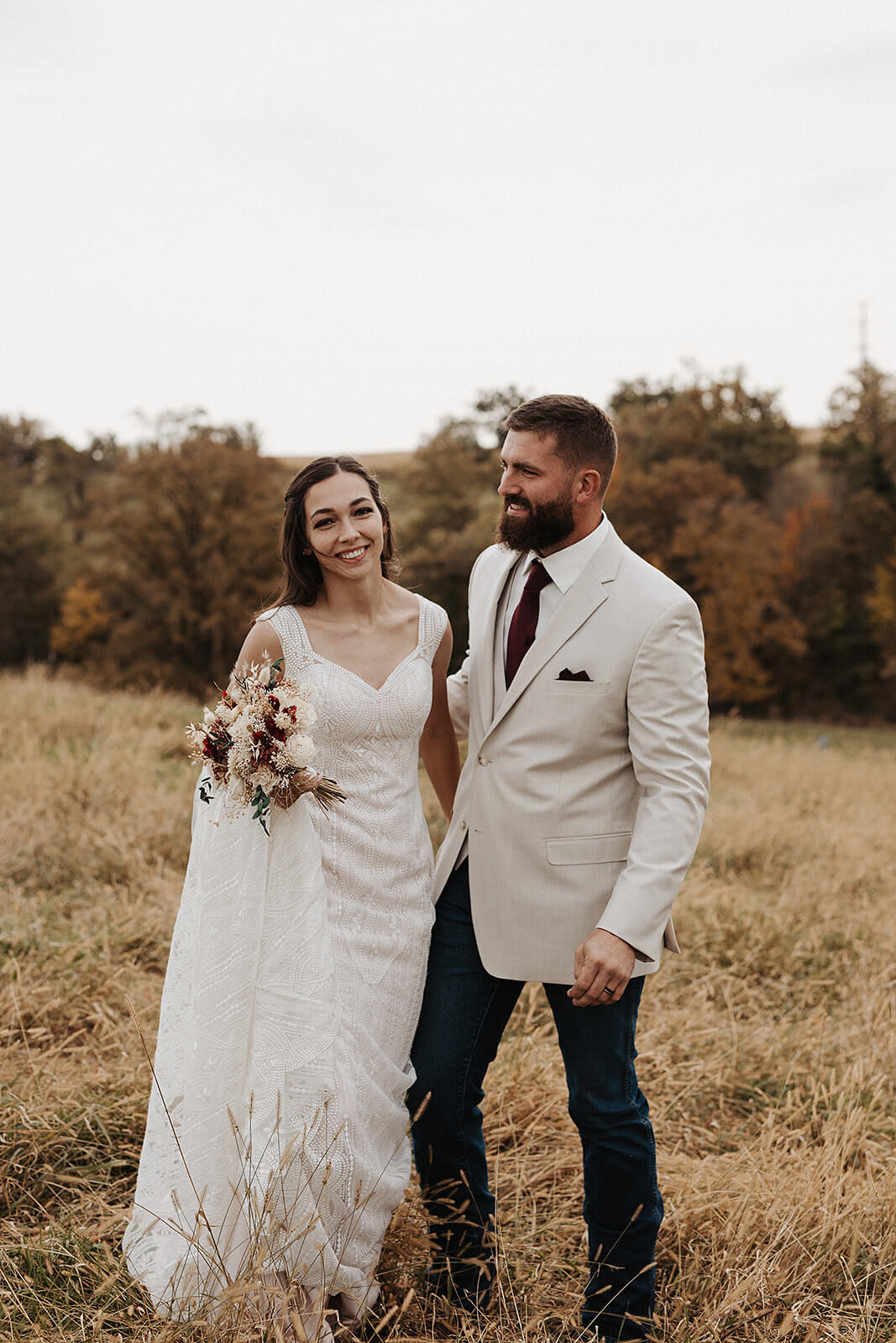 Bride and groom standing together in a golden fall field during Lancaster Wisconsin farmhouse wedding portraits