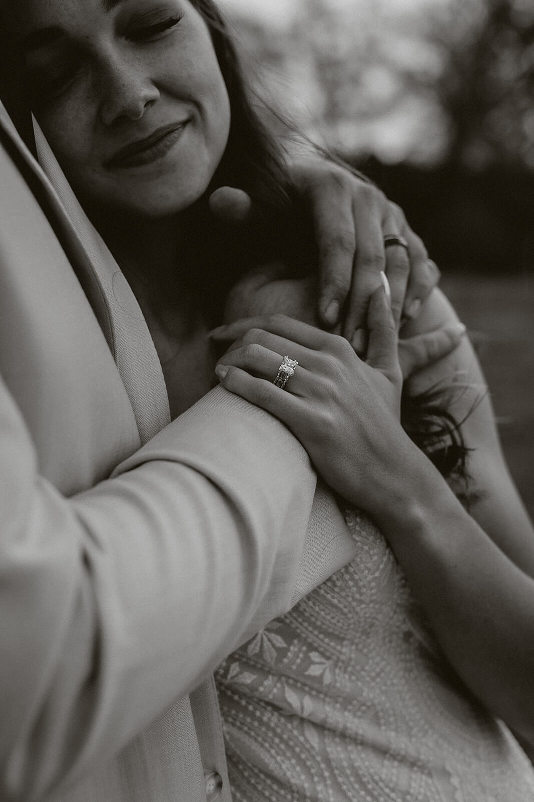 Black and white close-up of a bride's wedding ring resting on her groom's hand during Lancaster Wisconsin farmhouse wedding portraits