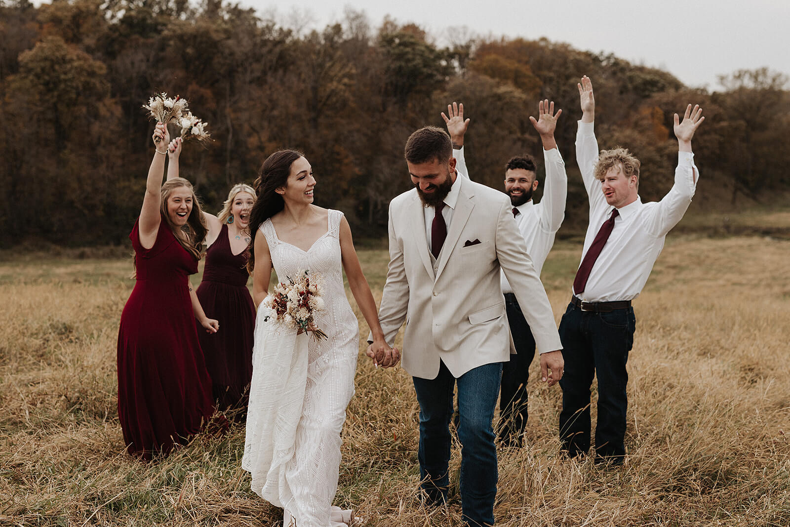 Wedding party celebrating together in a golden fall field after the ceremony at a Lancaster Wisconsin farmhouse wedding