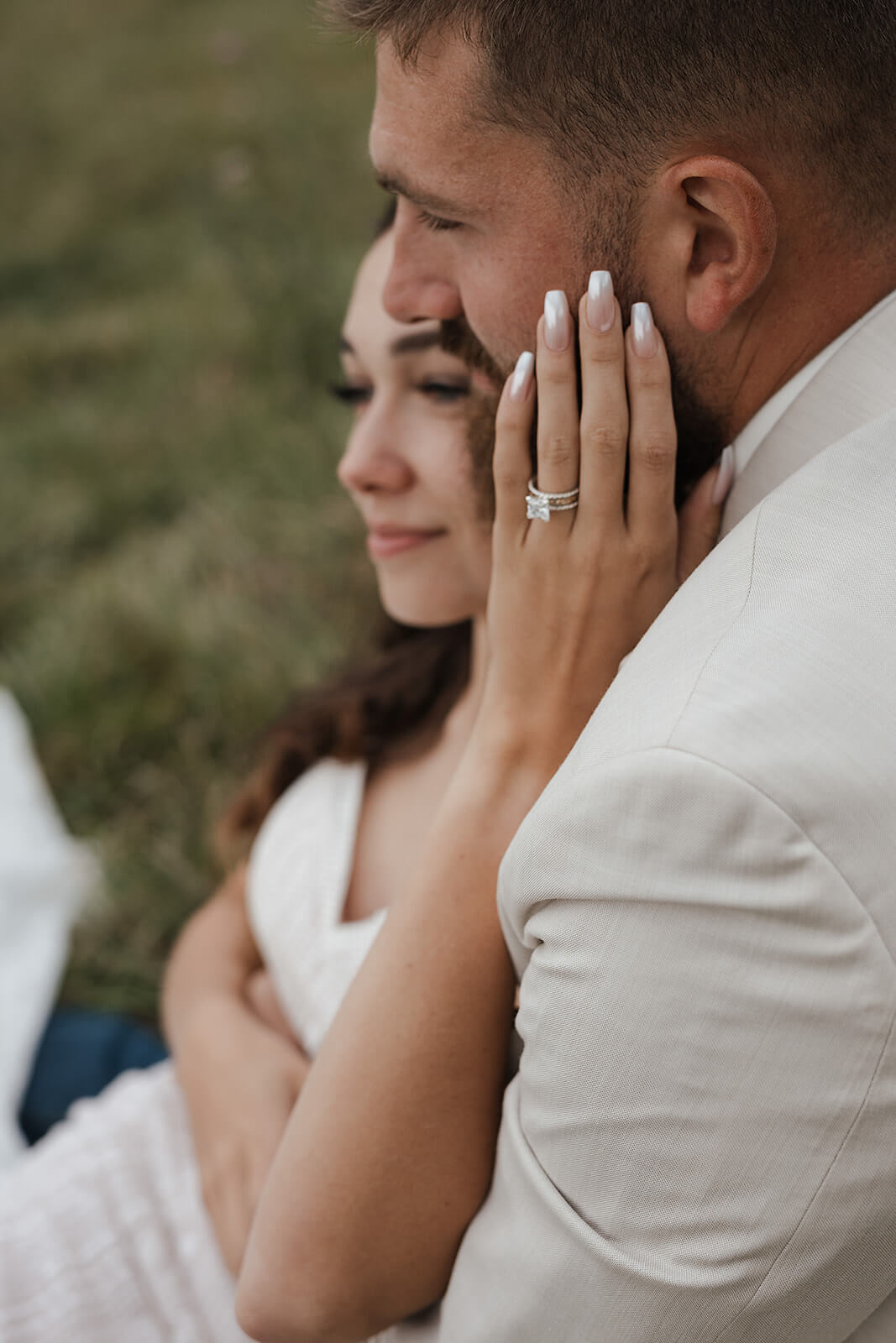 Close-up of a bride resting her hand on her groom's face showing her wedding ring during Lancaster Wisconsin farm wedding portraits