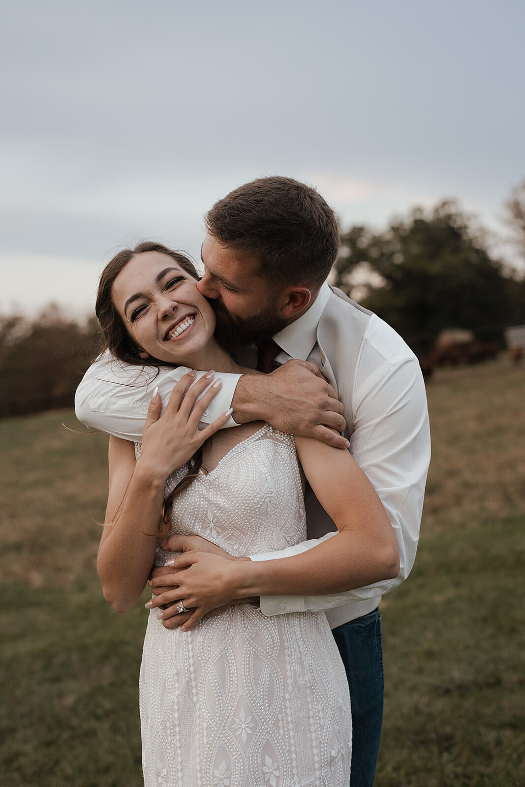 Bride and groom sharing a kiss in a green farm field during Lancaster Wisconsin wedding portraits