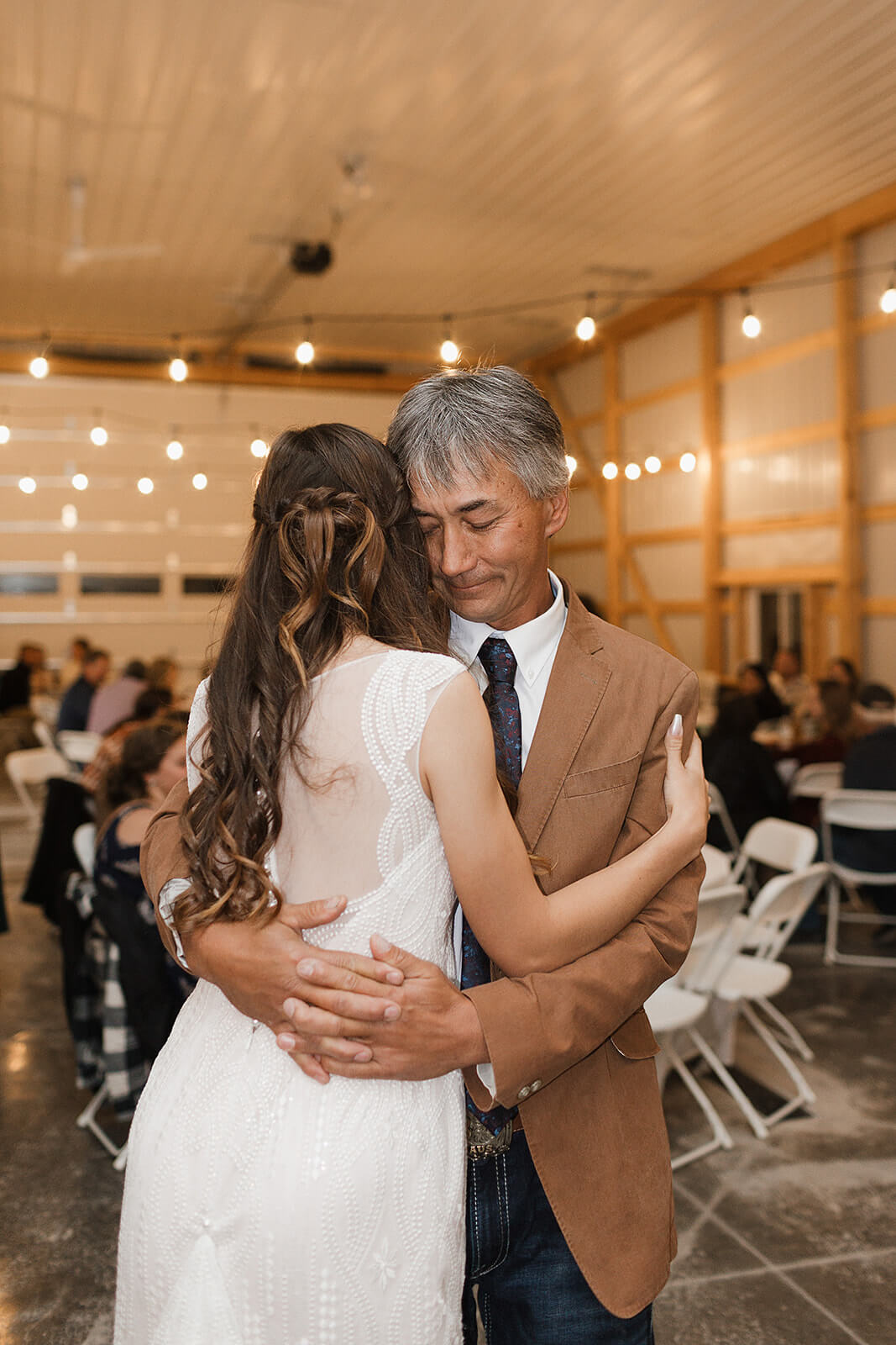 Bride and her father sharing an emotional hug during the father daughter dance at a Lancaster Wisconsin barn wedding reception