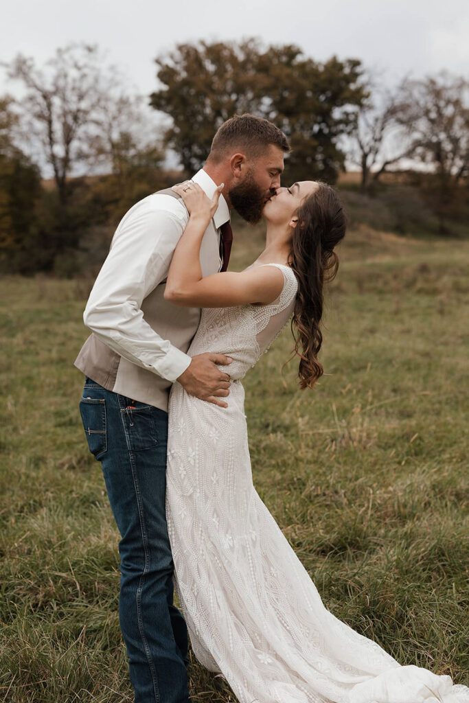 Bride and groom sharing a kiss in a green farm field during Lancaster Wisconsin wedding portraits